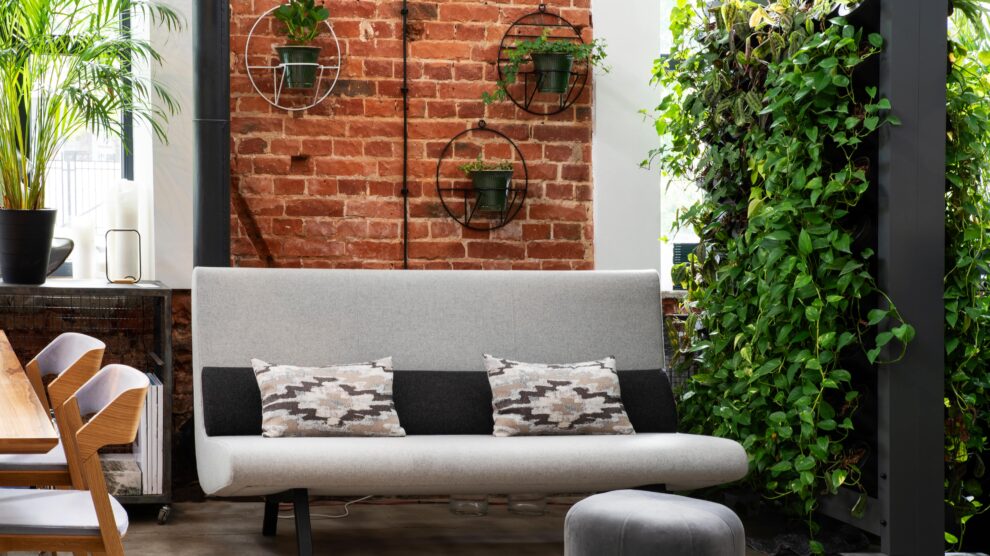 Ogród wertykalny w salonie – modernistyczne wnętrze z kanapą, ścianą z cegieł i ścianą z roślin